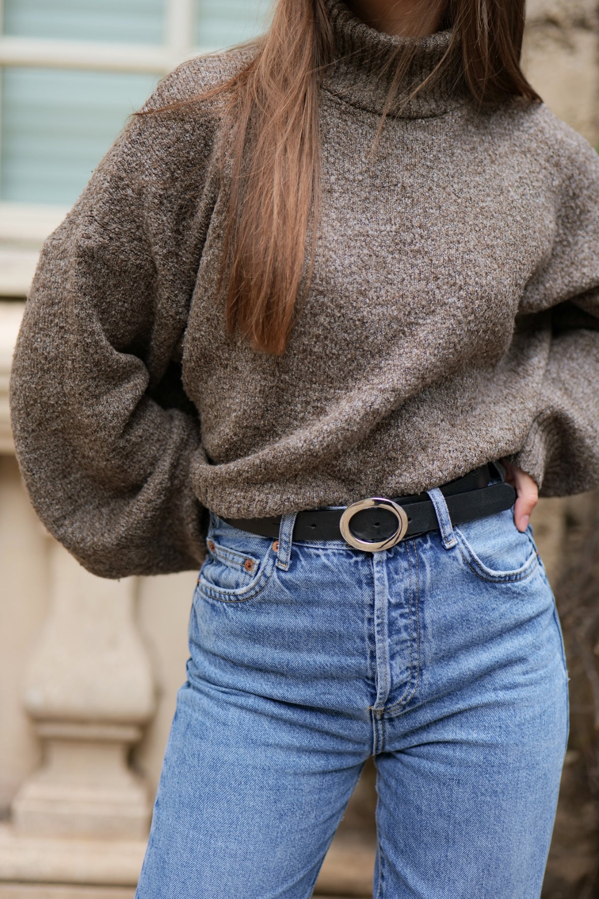 Femme portant la ceinture Simone fine en cuir noir sur un jean, boucle or