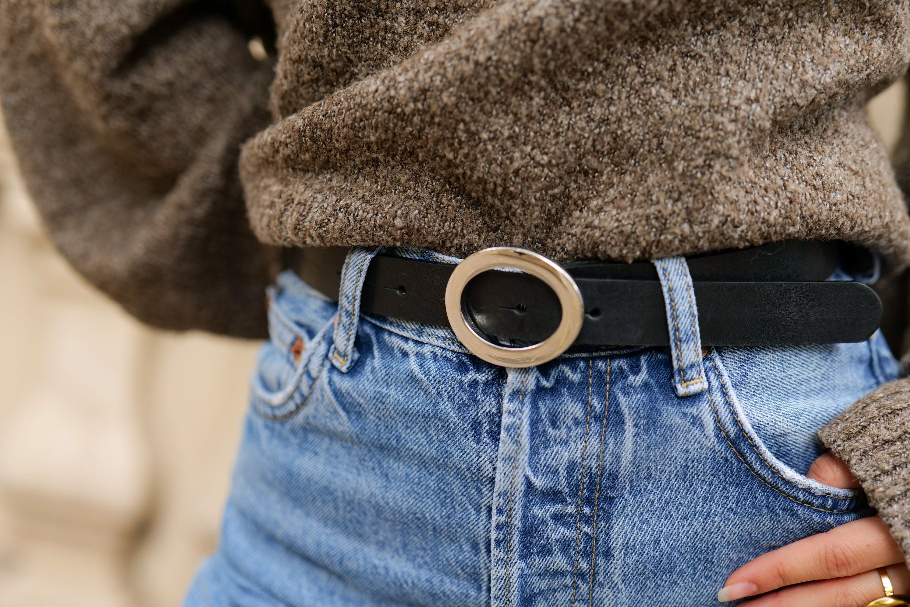 Gros plan sur la boucle ovale dorée de la ceinture Simone en cuir noir