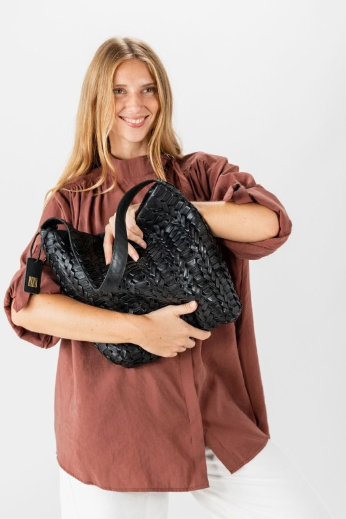 Sac Elk Biba en cuir tressé noir tenu dans les bras, relief du tressage