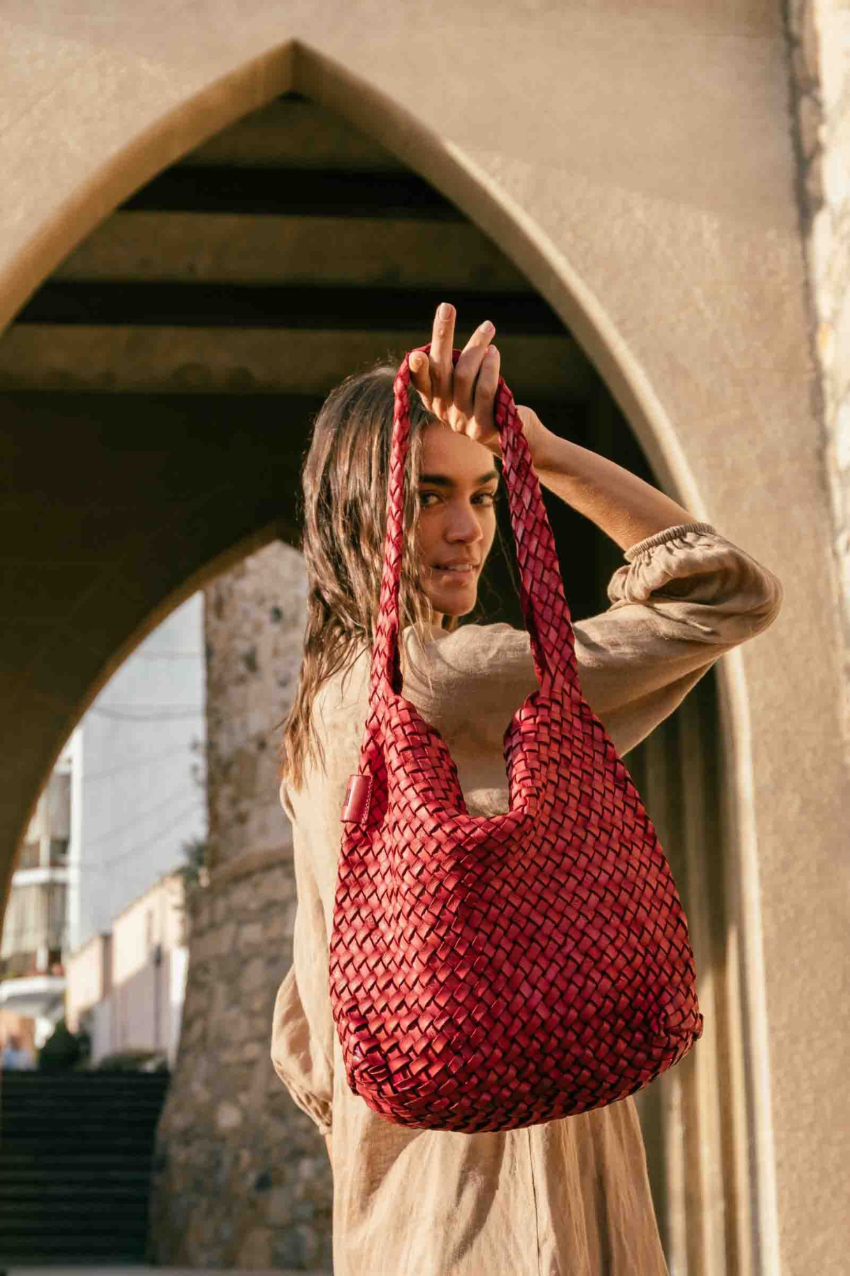 Sac hobo en cuir tressé rouge porté à l'épaule, modèle femme tendance en situation
