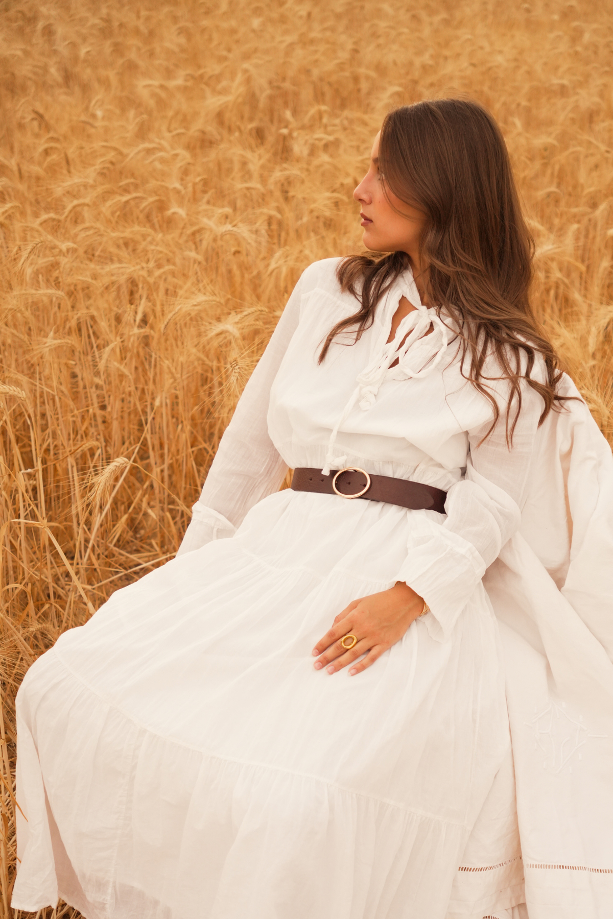 Ceinture femme en cuir marron Adèle Atelier Nappa portée sur une robe longue blanche dans un champ de blé