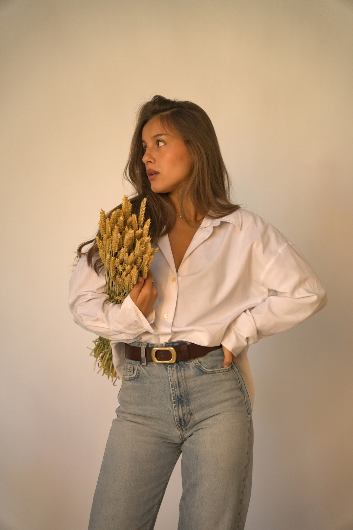 Ceinture en cuir marron foncé Adèle Atelier Nappa à boucle dorée, portée sur un jean taille haute