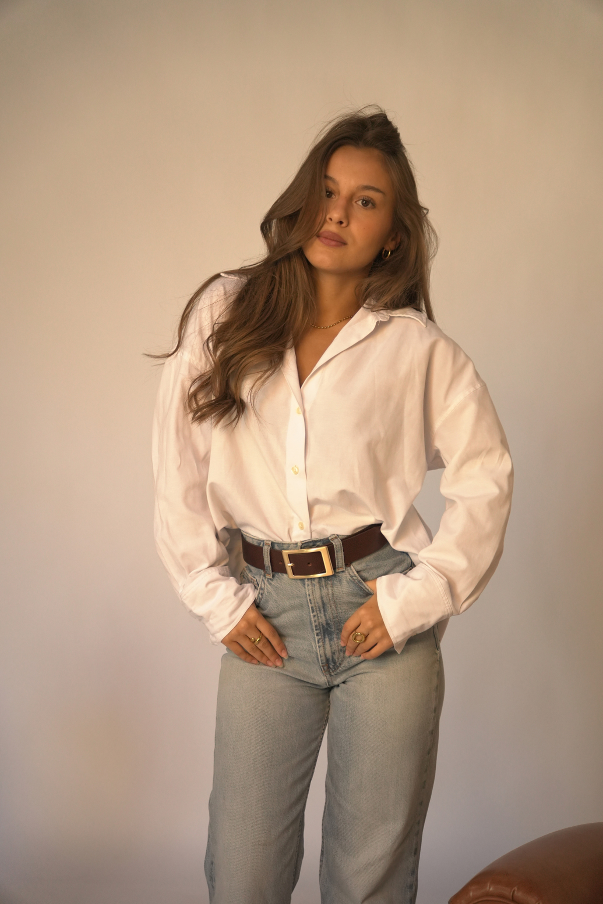Ceinture Charlotte Atelier Nappa en cuir marron foncé à boucle rectangulaire dorée, portée avec un jean taille haute et une chemise blanche.