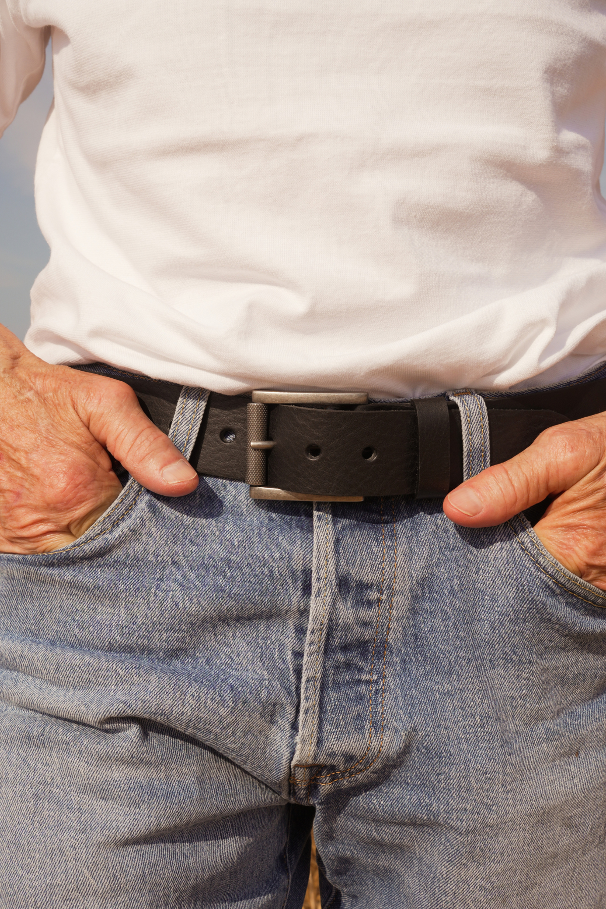 Ceinture homme Max Atelier Nappa en cuir noir à boucle à rouleau argentée, portée sur un jean avec un t-shirt blanc