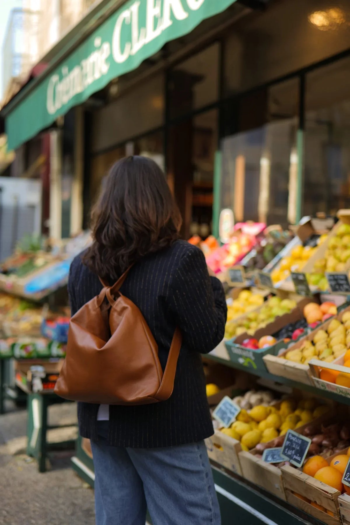 Sac Jérôme en cuir grainé camel porté en sac à dos devant un primeur