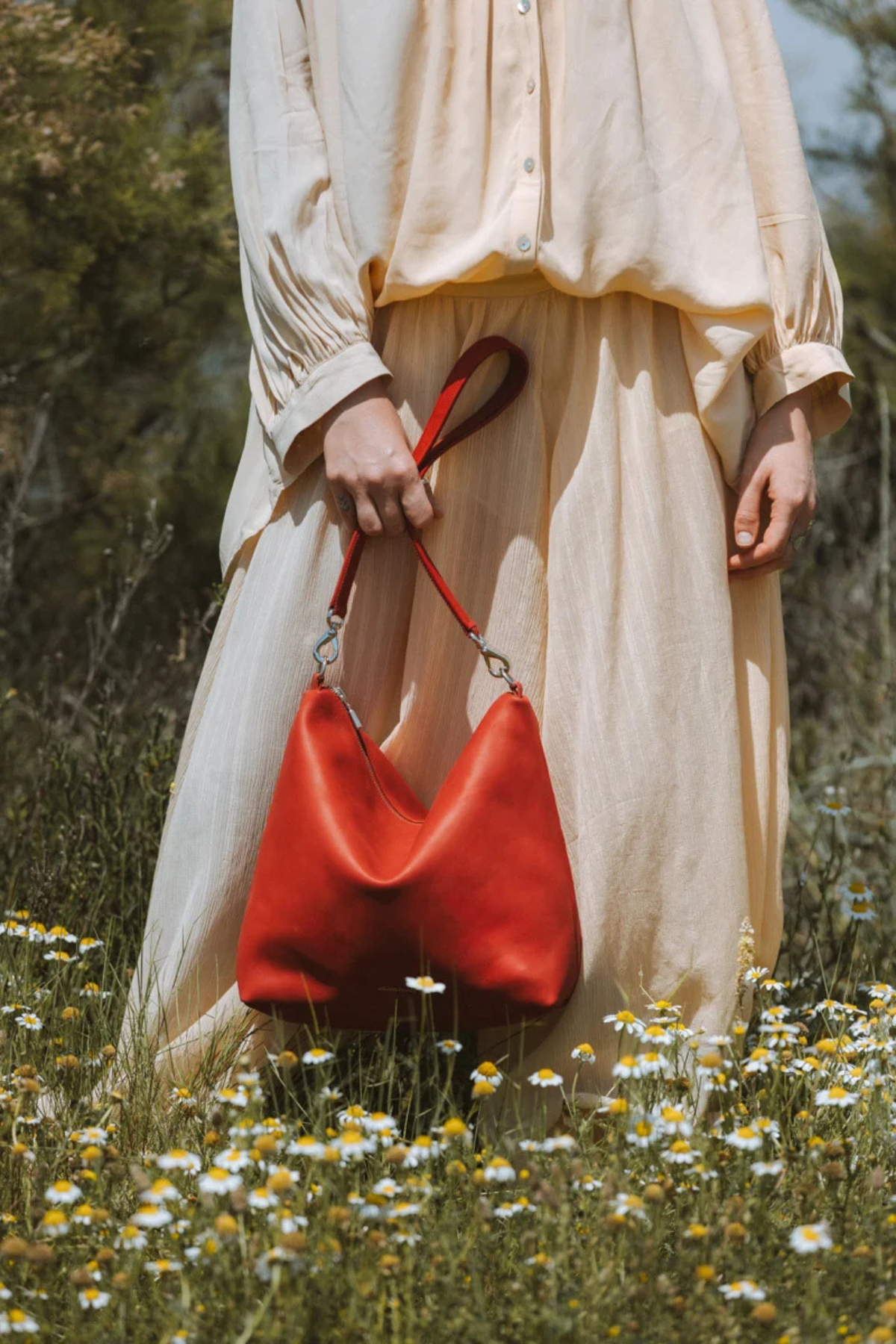 Sac seau zippé en cuir rouge Iliade Ateliers Fourès tenu à la main, cuir pleine fleur fabriqué en France